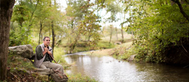 Man taking a break from hiking near creek